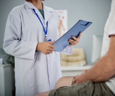 Doctor holding clipboard speaking with a patient